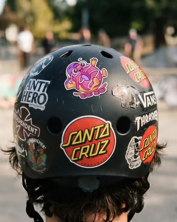 A pink donut character sticker on a skate helmet